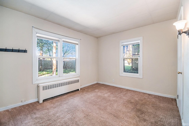 empty room with a wealth of natural light, carpet, and radiator