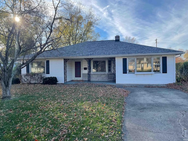 ranch-style home with a porch, a shingled roof, and a front lawn