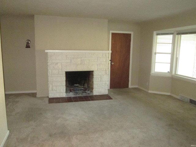 unfurnished living room with a stone fireplace and light carpet