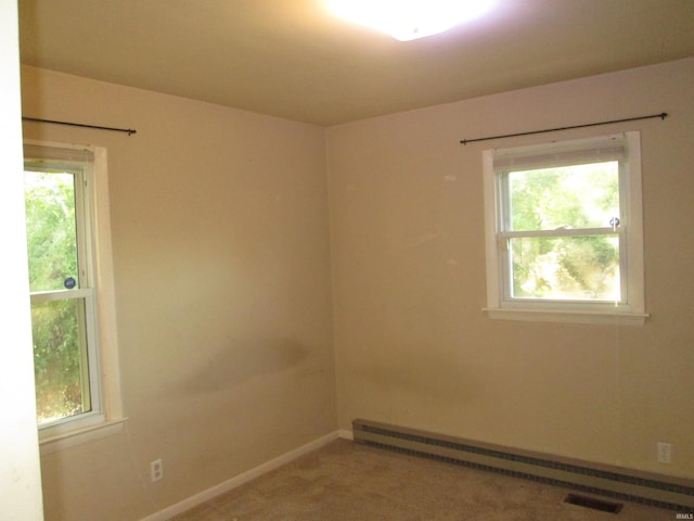 carpeted spare room with a baseboard heating unit and plenty of natural light