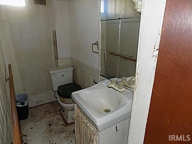 bathroom with vanity, toilet, and concrete flooring