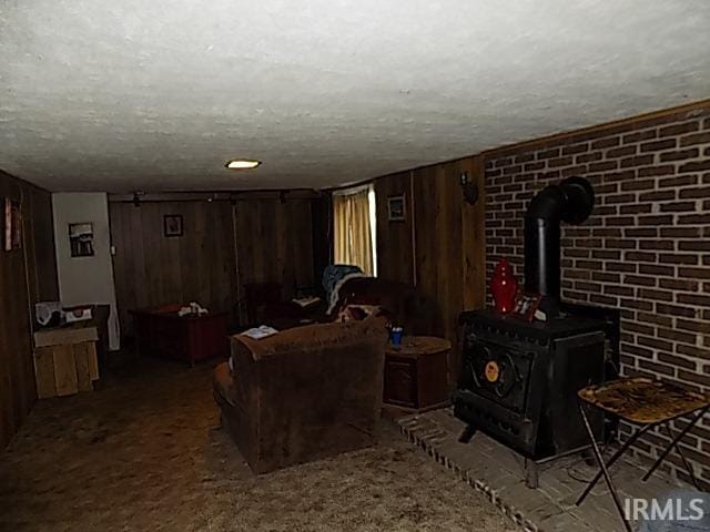 carpeted living room with a wood stove, a textured ceiling, and wooden walls