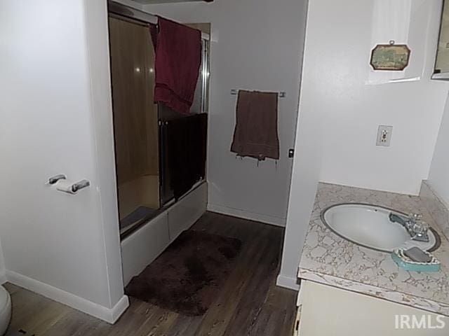 full bathroom with vanity, combined bath / shower with glass door, hardwood / wood-style flooring, and toilet