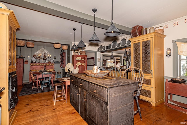 kitchen with a kitchen breakfast bar, light hardwood / wood-style flooring, dark brown cabinetry, and pendant lighting