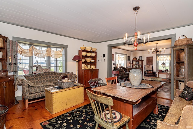 dining room with crown molding, hardwood / wood-style flooring, and an inviting chandelier