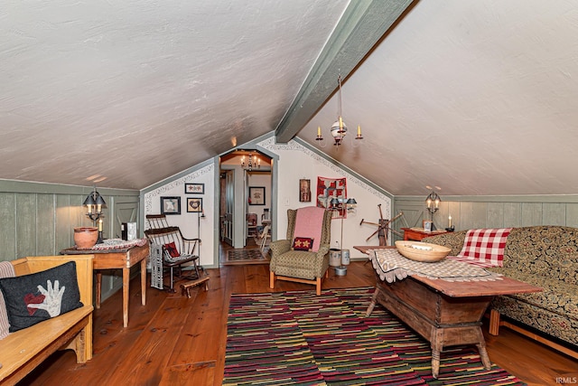 living area with lofted ceiling with beams, a textured ceiling, wooden walls, and hardwood / wood-style floors