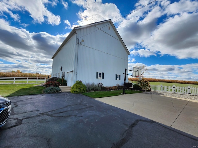 view of side of home featuring a yard and basketball court