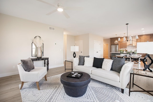 living room featuring light hardwood / wood-style floors and ceiling fan with notable chandelier