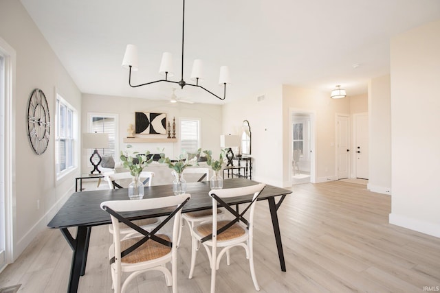 dining space with light hardwood / wood-style floors and ceiling fan with notable chandelier