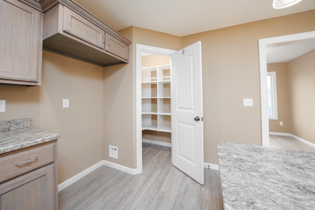 kitchen with light hardwood / wood-style flooring, light stone counters, and light brown cabinetry