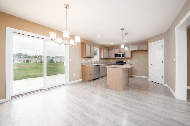 kitchen featuring light stone countertops, appliances with stainless steel finishes, a kitchen island, light hardwood / wood-style floors, and pendant lighting