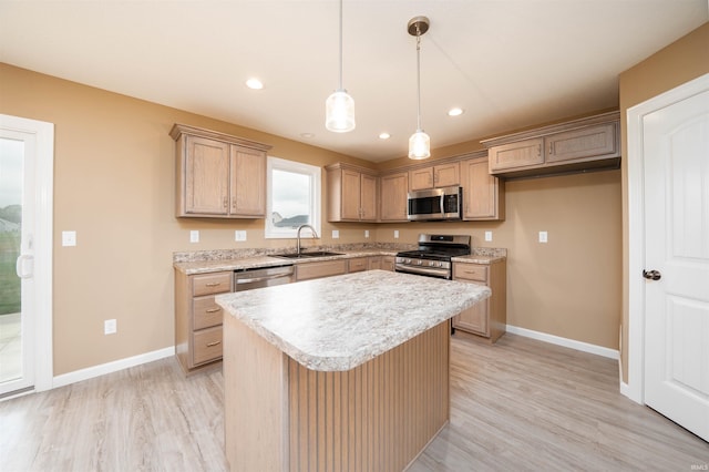 kitchen featuring sink, a center island, decorative light fixtures, light wood-type flooring, and appliances with stainless steel finishes