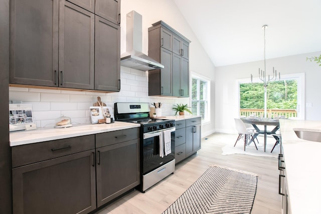 kitchen featuring gas stove, wall chimney exhaust hood, plenty of natural light, and pendant lighting