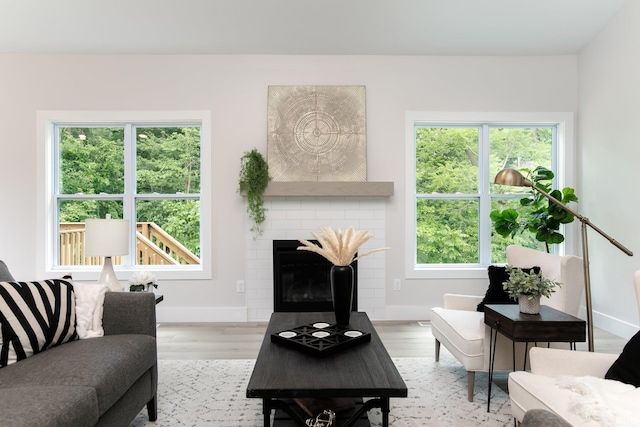 living room featuring light hardwood / wood-style floors, a wealth of natural light, and a brick fireplace