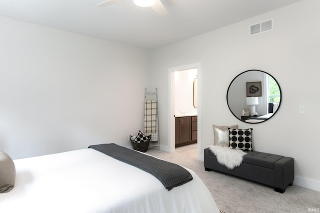 bedroom with ensuite bathroom, light colored carpet, and ceiling fan