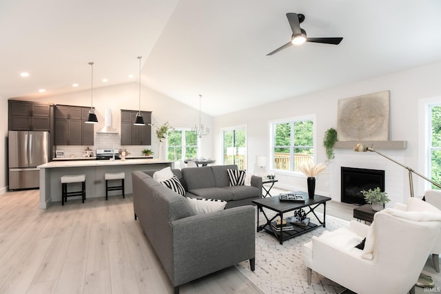 living room with vaulted ceiling, light hardwood / wood-style flooring, and ceiling fan with notable chandelier