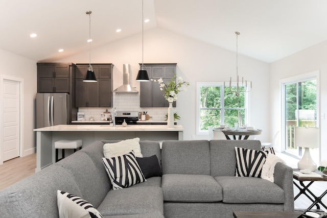 living room featuring high vaulted ceiling, sink, and light wood-type flooring