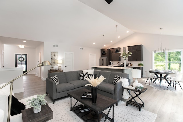 living room with lofted ceiling, sink, and light wood-type flooring