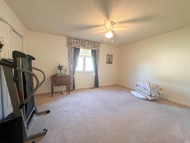 exercise room featuring a textured ceiling, light colored carpet, and ceiling fan