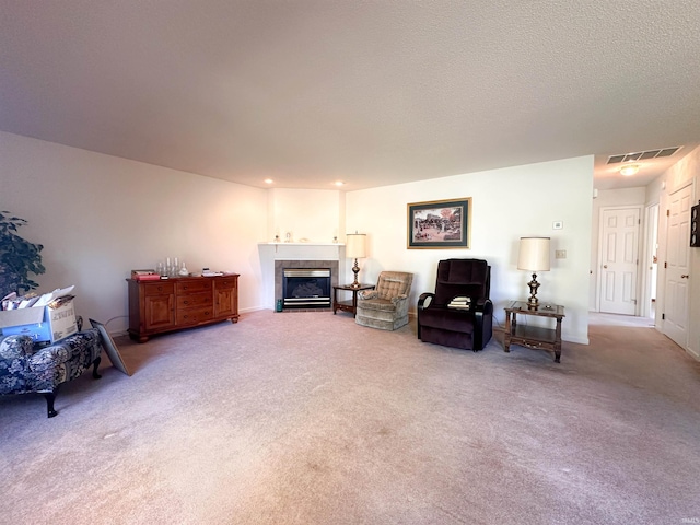 living area featuring a textured ceiling, a tiled fireplace, and light colored carpet