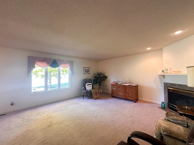 sitting room with light carpet, a textured ceiling, and a tile fireplace