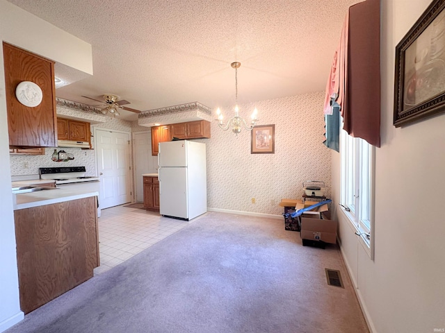 kitchen featuring a textured ceiling, hanging light fixtures, ceiling fan with notable chandelier, and white appliances