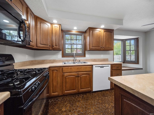 kitchen featuring a healthy amount of sunlight, black appliances, sink, and a textured ceiling