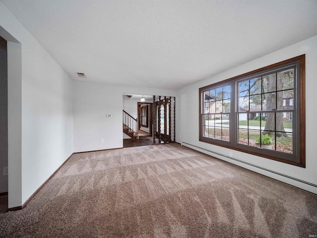 carpeted spare room with a baseboard heating unit and a textured ceiling