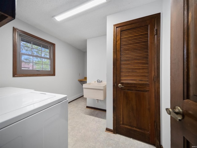 clothes washing area featuring washer / clothes dryer, a textured ceiling, and sink