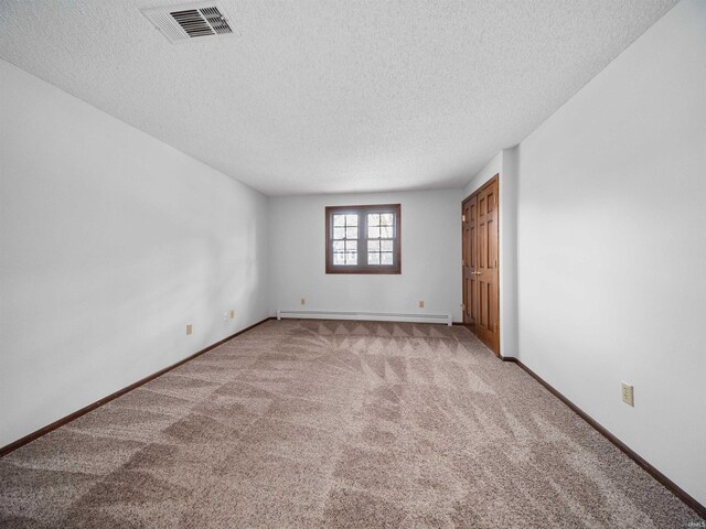 unfurnished room featuring a textured ceiling, baseboard heating, and light colored carpet