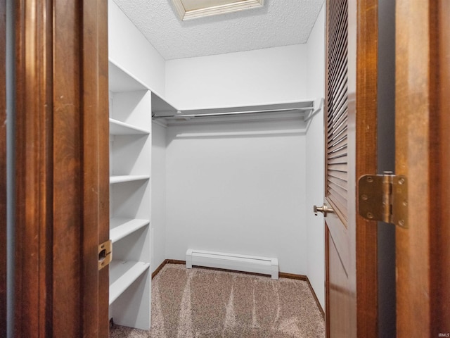 spacious closet featuring carpet floors and baseboard heating