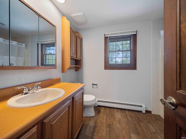 bathroom featuring toilet, baseboard heating, wood-type flooring, and a wealth of natural light