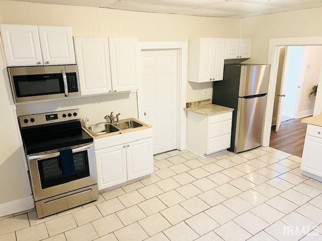 kitchen with white cabinetry, light tile patterned flooring, appliances with stainless steel finishes, and sink