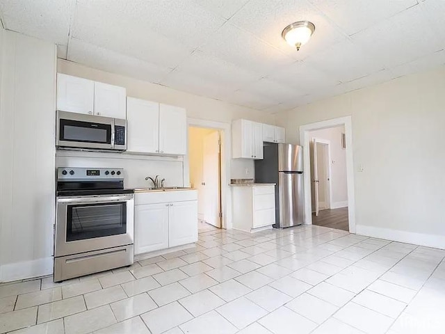 kitchen featuring appliances with stainless steel finishes, white cabinets, sink, and light tile patterned floors