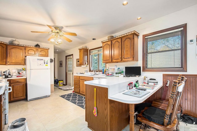 kitchen with a kitchen breakfast bar, kitchen peninsula, white appliances, and ceiling fan