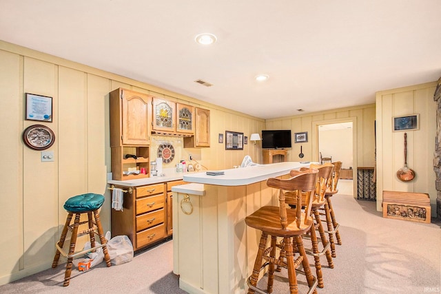 kitchen featuring light carpet, a breakfast bar, and light brown cabinetry