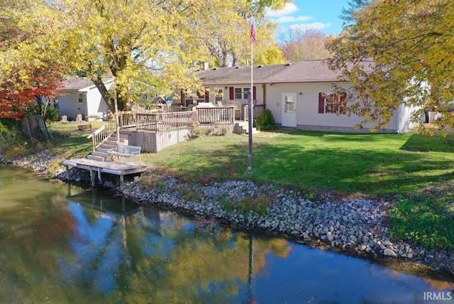 rear view of house with a deck with water view and a lawn