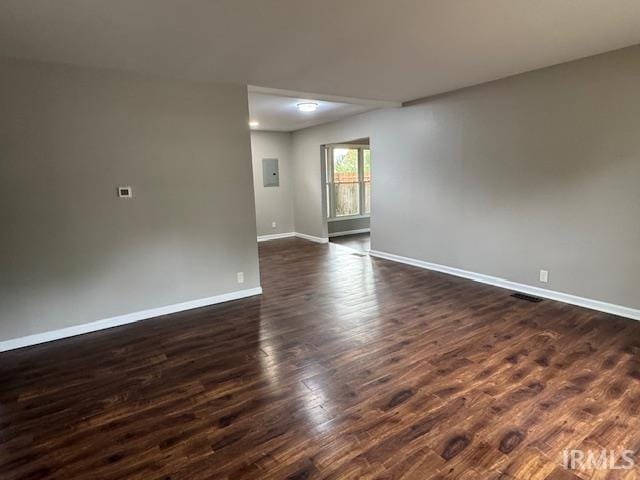 empty room with dark wood-type flooring and electric panel