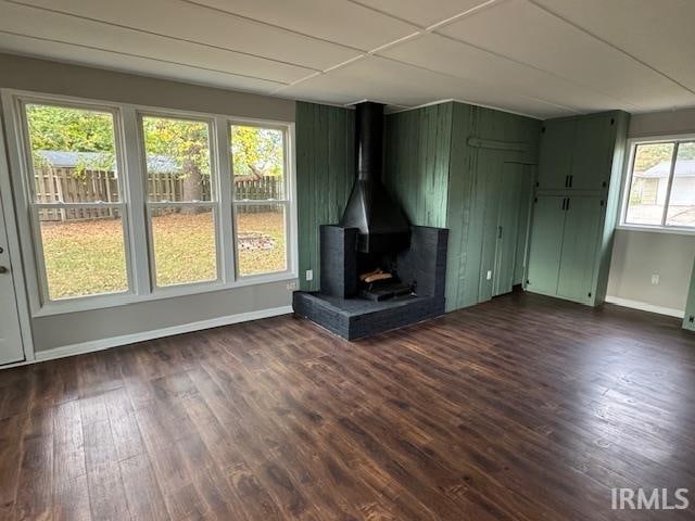 unfurnished living room featuring a wood stove and dark hardwood / wood-style flooring