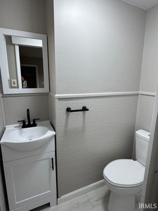 bathroom featuring vanity, toilet, and tile walls