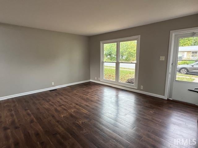 spare room featuring a wealth of natural light and dark hardwood / wood-style floors