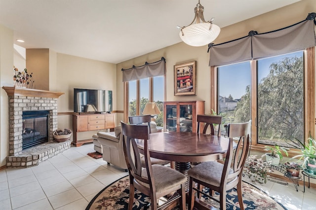 dining area with a brick fireplace and light tile patterned floors