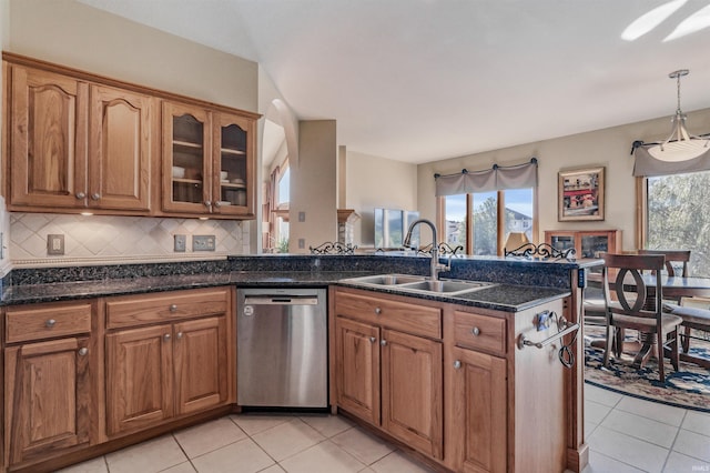 kitchen with decorative backsplash, stainless steel dishwasher, dark stone counters, sink, and decorative light fixtures