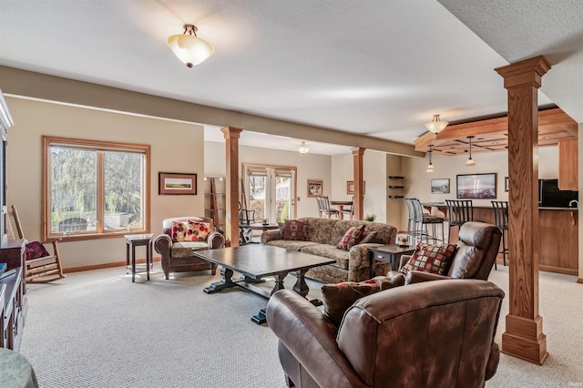 carpeted living room with decorative columns and a textured ceiling