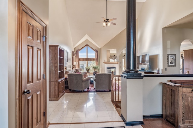 living room featuring ceiling fan, high vaulted ceiling, and light tile patterned floors