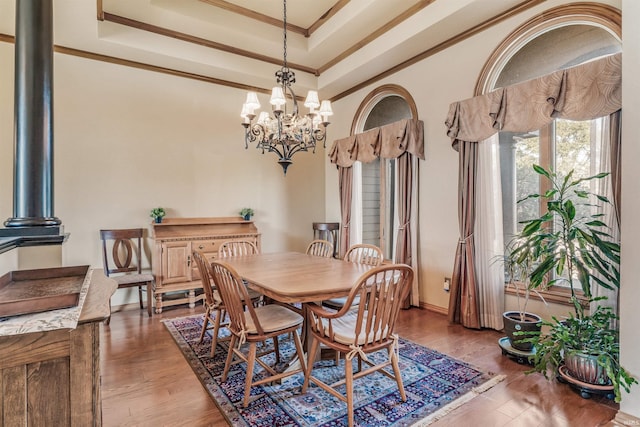 dining room with ornamental molding, a chandelier, a tray ceiling, and wood-type flooring