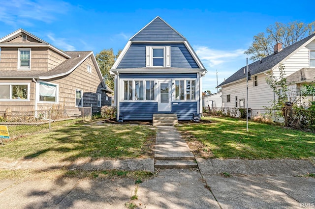 view of front of house with a front yard and a sunroom