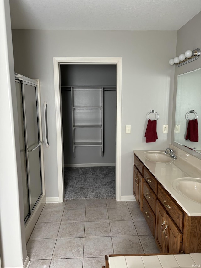 bathroom with vanity, an enclosed shower, a textured ceiling, and tile patterned flooring