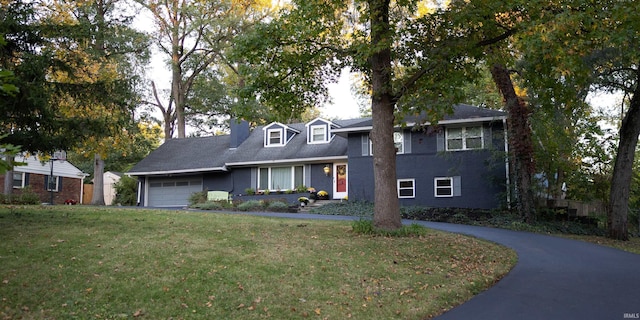 view of front facade with a chimney, a front yard, a garage, brick siding, and aphalt driveway