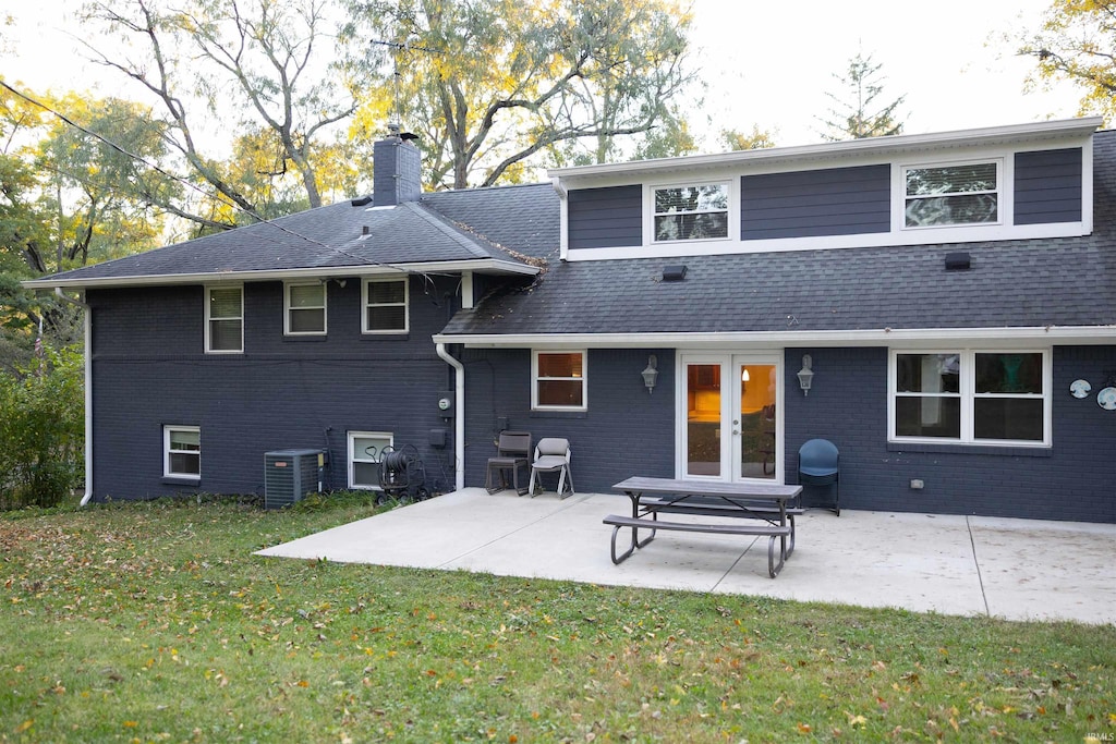 rear view of property featuring a lawn, a patio, a chimney, and brick siding